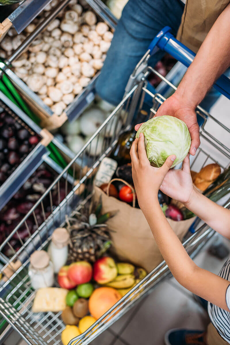 overhead view of little child helping parent during shopping in grocery shop