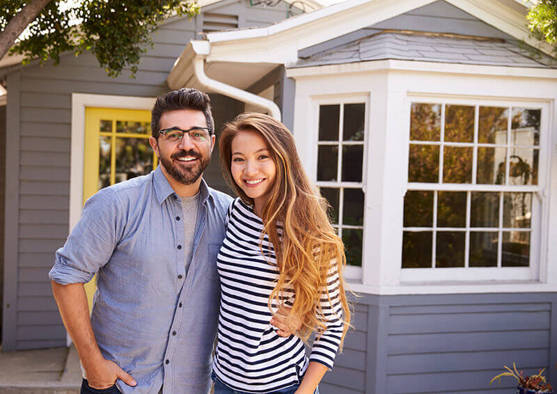 smiling couple in front of house