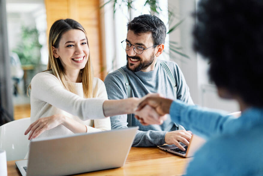 smiling couple shaking hands with banker