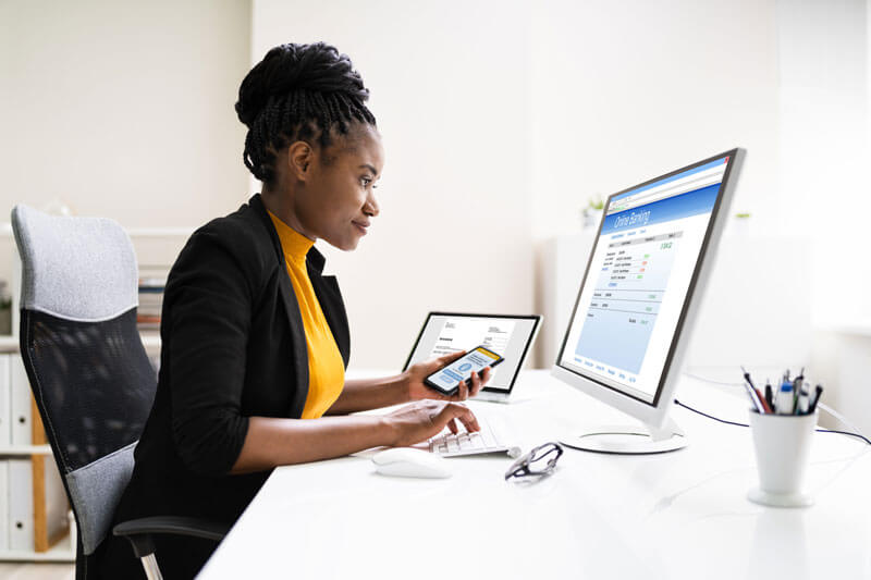 woman sitting at computer with mobile phone